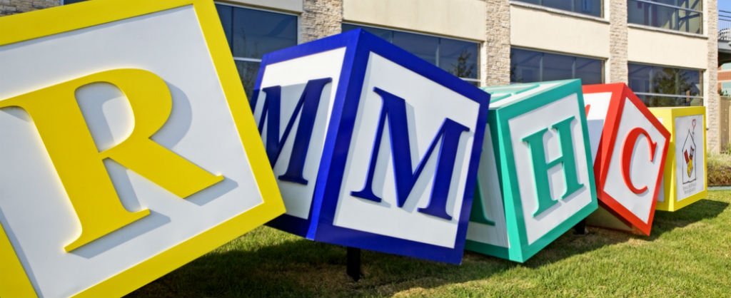 giant child-style play blocks spelling R M H C and rmhc logo