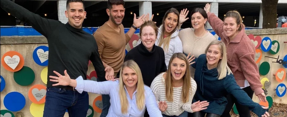 members of friends of the house smiling together for a group photo with their hands raised