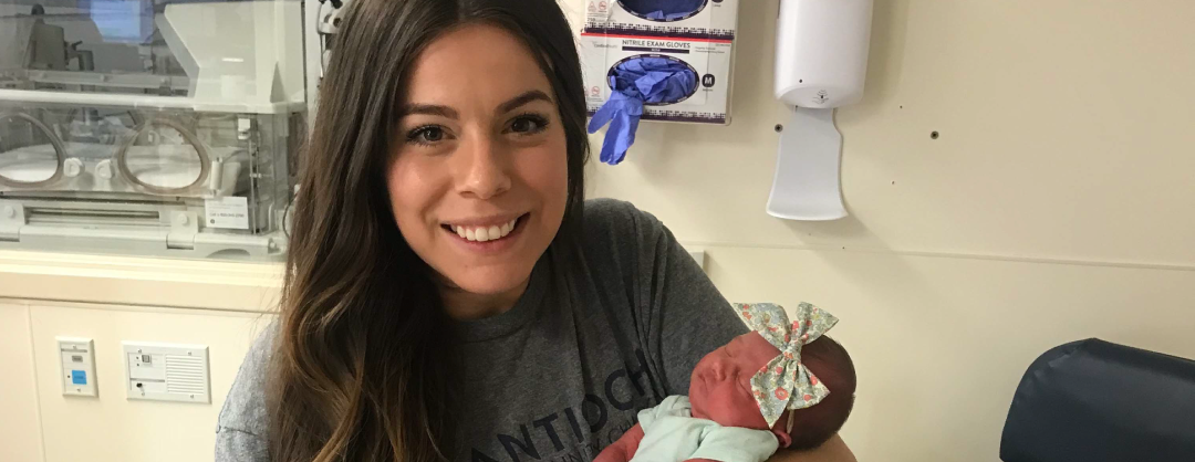 mother holding newborn child in hospital room and smiling